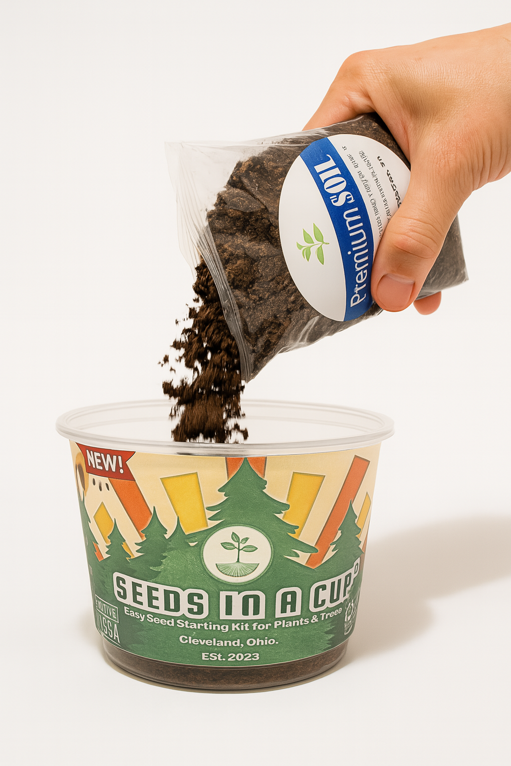 Hand pouring soil from a container labeled 'Seeds in a Cup' onto a white how to grow from seed tree seed background